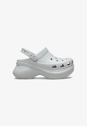 Sabots blancs en matériau durable, dotés de trous de ventilation, d'une sangle arrière pour le soutien, et d'une semelle épaisse pour plus de hauteur.
