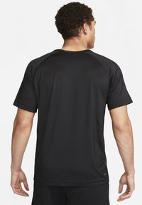 Camiseta atlética negra de manga corta hecha de un tejido transpirable, con un cuello redondo y mangas raglán, de textura suave.