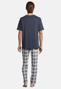 T-shirt in cotone navy abbinato a pantaloni del pigiama a quadri grigi e bianchi realizzati in tessuto morbido, con vita elastica e vestibilità slim.