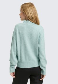 Mi�ętowy, dziany sweter z wysokim, imitującym golf kołnierzem, ściągaczami na rękawach i u dołu. Charakteryzuje się opuszczonymi ramionami i luźnym krojem.