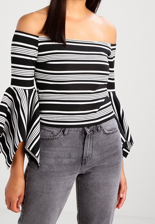 Top scollato con righe orizzontali bianche e nere, con ampie maniche a campana. Abbinato a jeans grigi a vita alta.