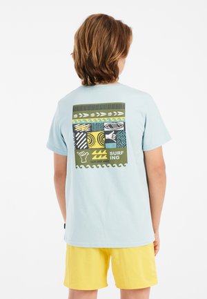 T-shirt in cotone azzurro chiaro con una grafica colorata sulla parte posteriore, caratterizzata da motivi e dalla parola "SURFING" in verde.