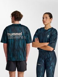 Man met de rug naar de camera en vrouw met gekruiste armen, beiden dragen bijpassende donkerblauwe, gemêleerde hummel sportkleding tegen een witte achtergrond.