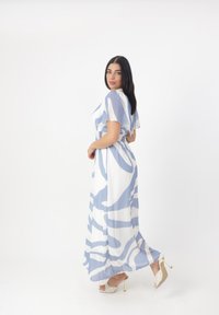 Robe maxi en tissu léger, avec un motif abstrait bleu et blanc, manches courtes, taille smockée et ourlet fluide.