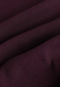 Tume burgundia soonik kangas pehme tekstuuriga, millel on vertikaalsed jooned ja kerge sära, mida kasutatakse sageli riietes ja polstrites.