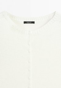 Biały dziergany kardigan z małymi białymi guzikami z przodu i czarną metką Massimo Dutti przy dekolcie.