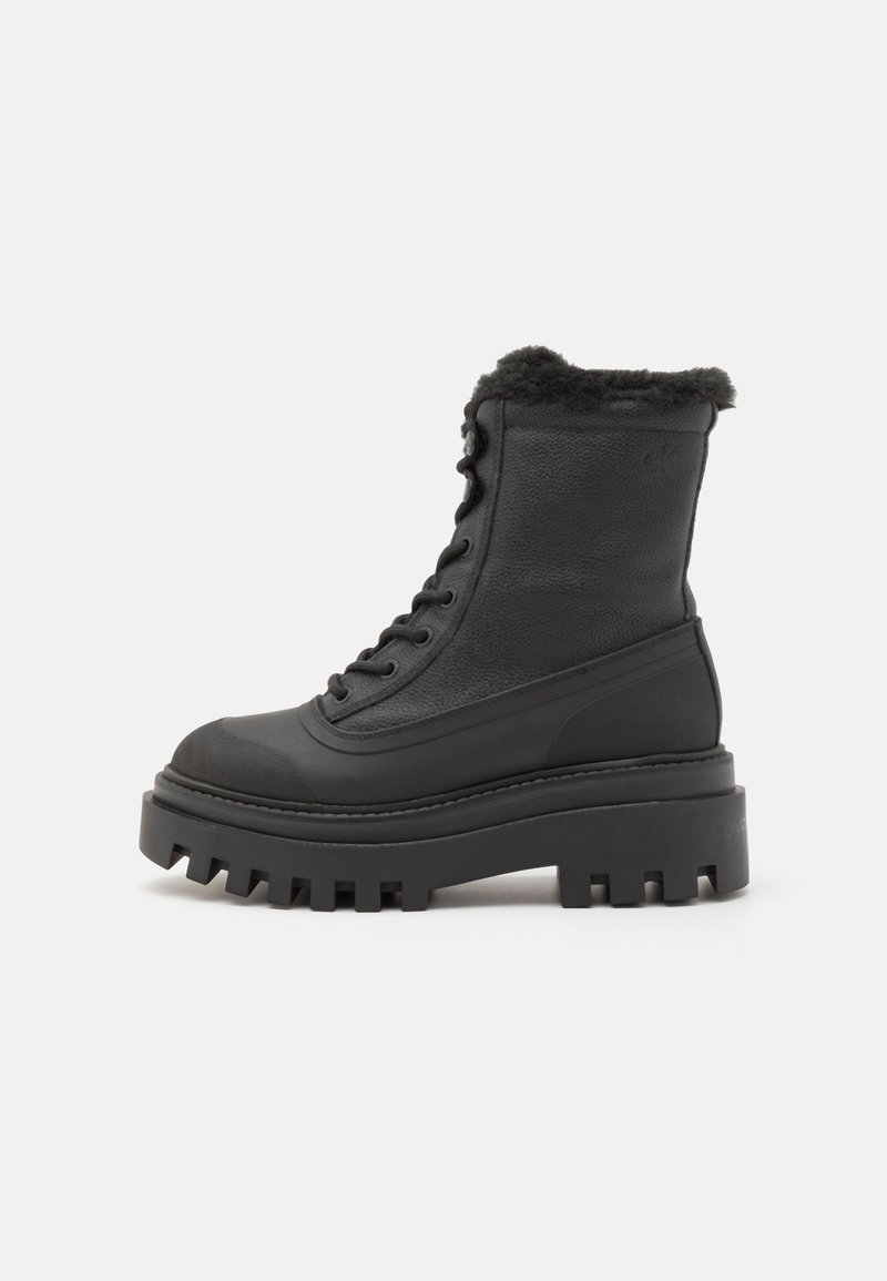 Botine negre cu un superior din piele texturată, vârf rotund și talpă groasă cu o margine zimțată. Captușite cu blană moale la mansetă.