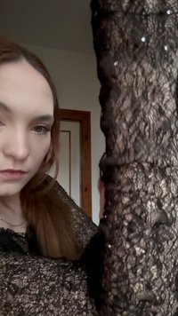 Schwarzes Spitzenoberteil mit aufwendigen Blumenmustern und weicher Textur, versehen mit dezenten Pailletten und langen Ärmeln. Eingebettet in eine neutrale Umgebung.