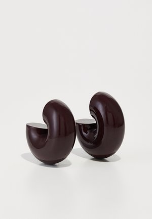 Esculturas curvadas en un burdeos profundo, con un acabado brillante, que presentan recortes en forma de media luna y una textura suave, asemejando formas abstractas de caracol.