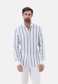 Camicia leggera a maniche lunghe con strisce verticali blu e bianche, frontale con bottoni, colletto e polsini bianchi a contrasto. Tessuto di lino testurizzato.
