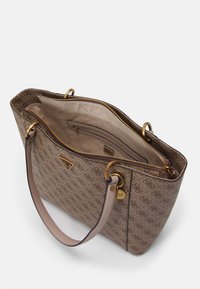 Sac cabas à motifs marron avec ferrures dorées et double anses. L'intérieur comprend une poche zippée et une doublure beige. Forme rectangulaire.