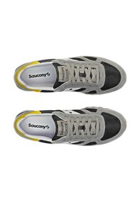 Sneakers Saucony Shadow grigi e neri con tomaia in mesh e suede, accento giallo sul tallone e lacci testurizzati, con logo bianco sulla linguetta.