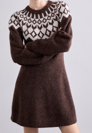 Robe en tricot marron avec un empiècement blanc à motifs. Dotée de manches longues et d'une texture douce, elle arrive au-dessus du genou avec une coupe décontractée.