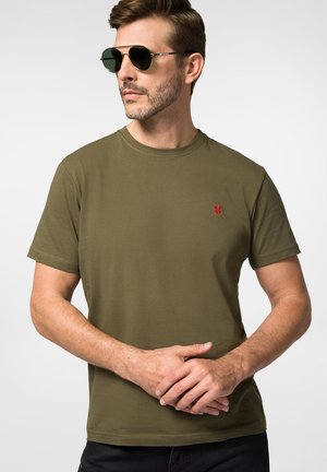Oliwkowy bawełniany t-shirt z krótkim rękawem i okrągłym dekoltem, z małym czerwonym logo na lewej piersi. Gładka faktura, luźny krój.