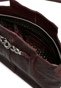 Bolso de cuero burdeos oscuro con detalles de cadena plateada, cremallera abierta que revela un interior negro con un patrón de lunares dorados y una etiqueta de marca de cuero.