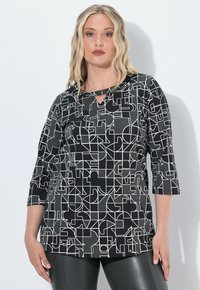 Mustavalkoinen kuviollinen paita, jossa on kolmanneksen mittaiset hihat, avainaukkokaulus ja geometrinen kuvio sileällä kankaalla.