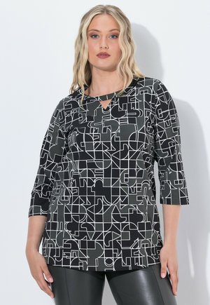 Top con motivo bianco e nero con maniche a tre quarti, caratterizzato da un collo a chiave e un design geometrico su un tessuto liscio.