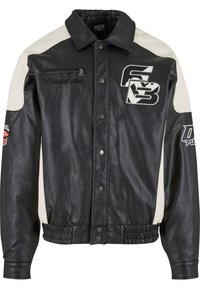 Veste en cuir noir avec accents blancs sur les épaules. Comprend une poche avant zippée, une fermeture à pression, et des logos sur la poitrine et la manche. Finition texturée.