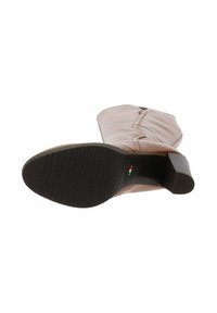 Bottine en cuir rose avec un talon carré, semelle noire texturée et détail de fermeture éclair sur le côté. Fini lisse et accents de couture minimaux.