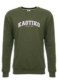 Sudadera verde oliva de algodón suave, con cuello redondeado, mangas largas y texto blanco "KAOTIKO EST.1999" en el pecho.