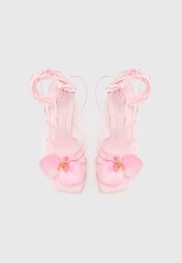 Roze hakken sandalen met een bloemenaccent. Transparante banden kruisen over een gladde, vierkante teenbasis. Gechmodderd bloemdetail.
