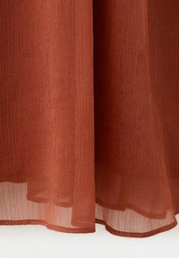 Tissu transparent couleur rouille avec une texture verticale visible et un ourlet légèrement incurvé en bas.