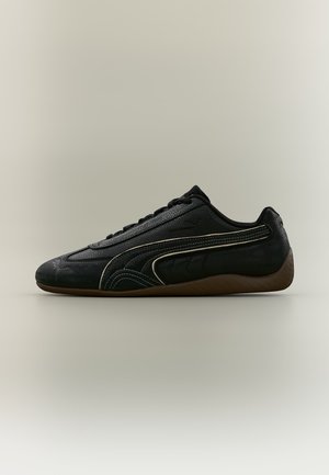 Lavprofileret sort lædersneaker med beige syninger og gummisål, vist fra siden på en neutral baggrund.