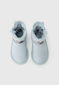 Stivali blu in morbida suede con fodera pelosa, caratterizzati da una finitura luccicante e da una fascia decorativa attorno alla caviglia.