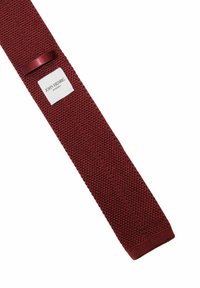 Burgundyröd stickad fluga med en texturerad tyg, som har en liten vit etikett med texten "JOHN HENRIC" och en satinaccent.