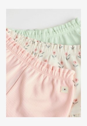 Tres pares de pantalones cortos de canalé en rosa, verde y con un estampado floral. Cinturas elásticas con detalles de volantes y una pequeña etiqueta de tela en los pantalones cortos rosas.