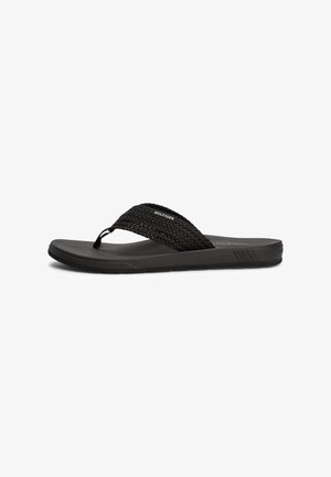 Black flip-flop sandal with woven strap, textured footbed, and flat sole. Features include a logo on the strap and a minimalist design.