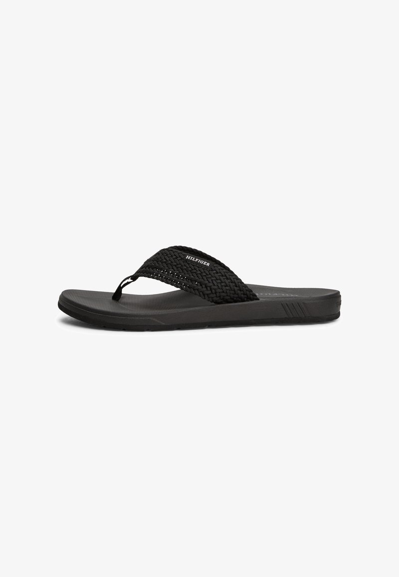 Sorte flip-flop sandaler med vevd stropp, teksturert såle og flat såle. Funksjoner inkluderer et logo på stroppen og et minimalistisk design.