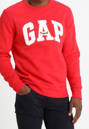 Maglione girocollo rosso con il logo bianco "GAP" sul petto e "Original" in una scrittura più piccola. Realizzato in morbido tessuto con polsini a costine.