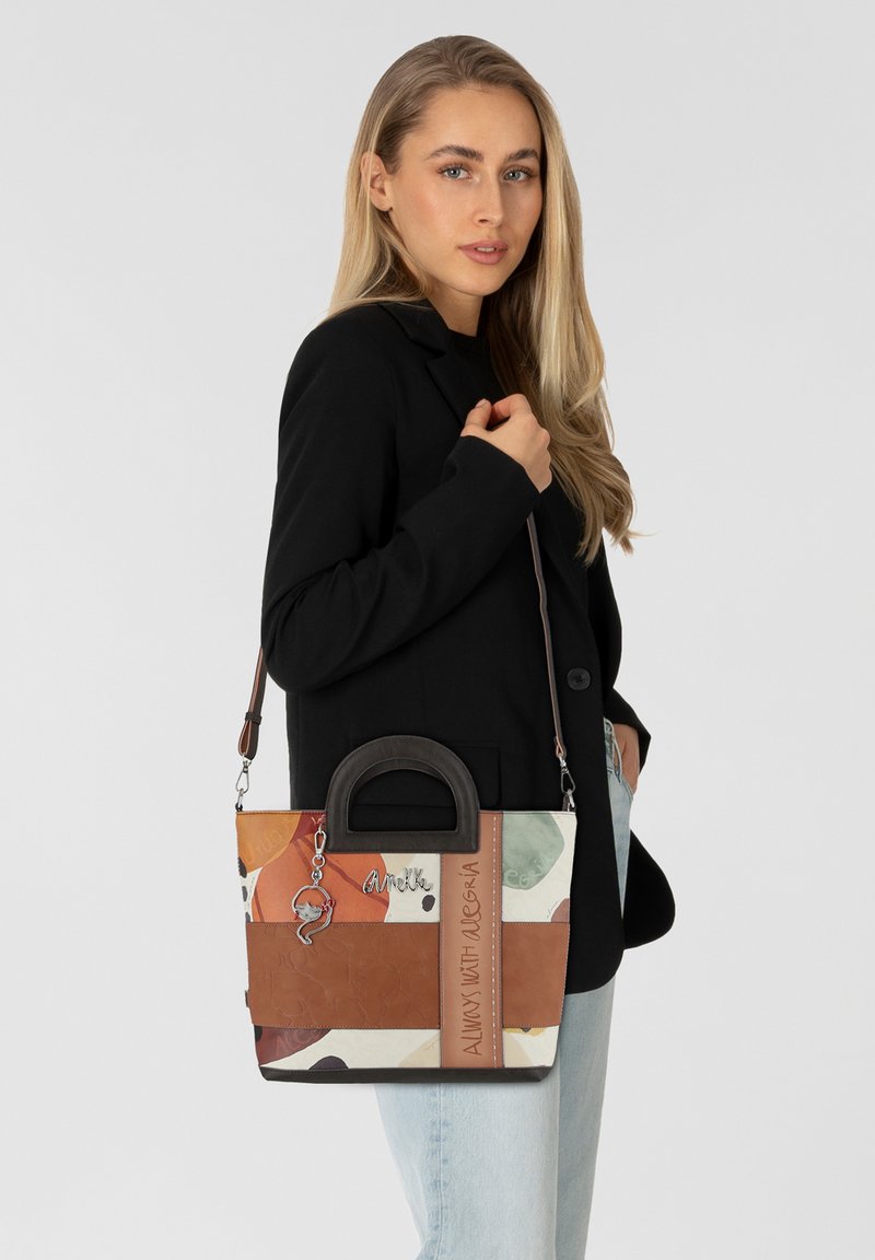 Sac à main multicolore en cuir, présentant une forme structurée, des poignées doubles et une bandoulière réglable. Décoré d'un charme et de détails gravés.