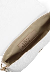 Witte leren handtas met structuur, geopend om de beige stoffen binnenkant en een "Made in Italy" label van echt leer te tonen.