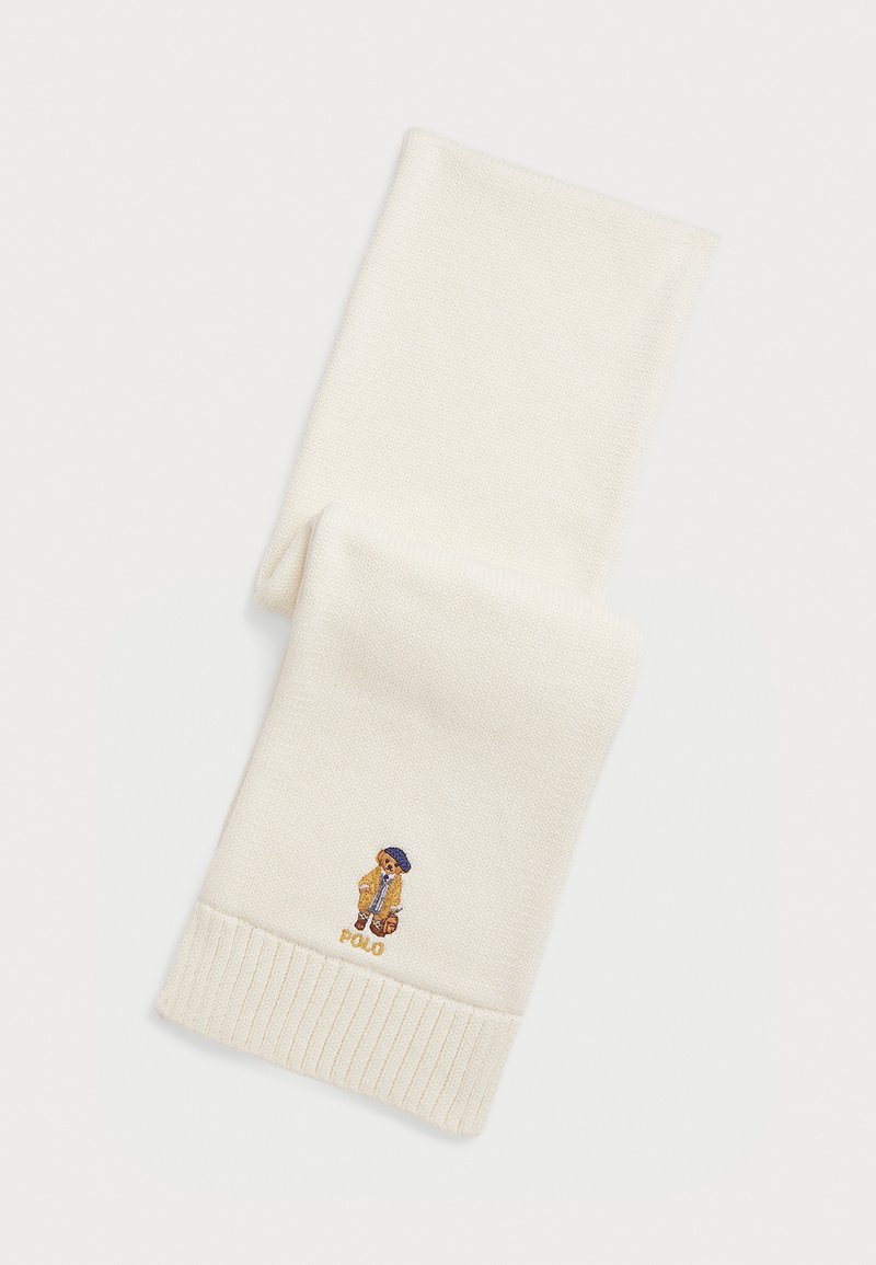 Hvit strikket skjerf med ribbestrikkede ender og et brodert bjørne-design iført en gul frakk og blå hatt, med "Polo"-tekst i gull.