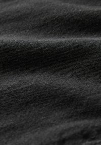 Schwarzer Stoff mit glatter Textur, der sichtbare Falten und einen leichten Glanz aufweist. Das Material wirkt weich und leicht.