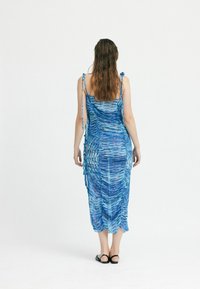 Blaues, gemustertes Kleid aus leichtem Stoff, mit einem figurbetonten Design, verstellbaren Trägern und einer Länge bis zur Mitte der Waden.