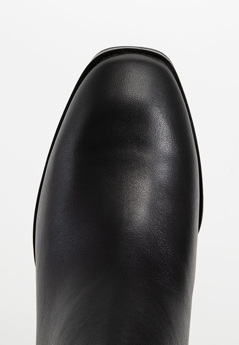Botte en cuir noir avec un bout arrondi élégant et une texture lisse. Présente des coutures minimales et une silhouette droite et épurée.