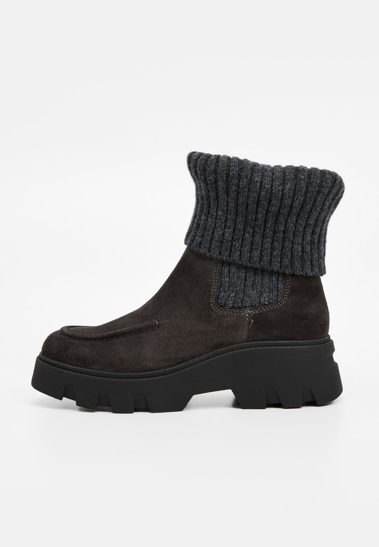 Stivali alla caviglia in suede marrone scuro con una robusta suola platform nera e un polsino lavorato a coste grigio scuro. Texture liscia con design minimalista.
