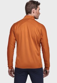 Herrenhemd mit langen Ärmeln aus strukturiertem, brennend orangefarbenem Stoff, mit Stehkragen und Raglanärmeln. Verfügt über flache Nähte und eine figurbetonte Passform.