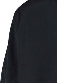 Maglietta nera a maniche lunghe in tessuto morbido e liscio. Presenta una vestibilità comoda con cuciture delicate e un scollo arrotondato, ideale per essere indossata a strati.