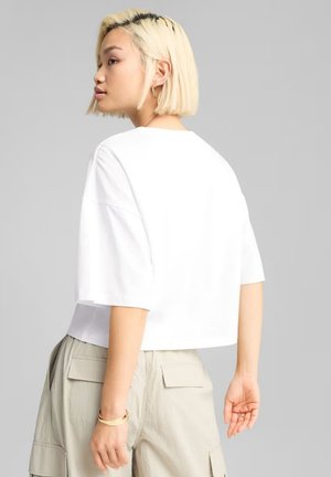 Hvid cropped t-shirt med korte ærmer, rund hals og afslappet pasform. Tekstureret bomuldsstof og synlige syningsdetaljer.