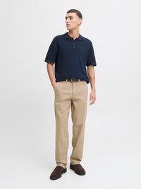 Námornícky polo tričko s krátkym rukávom a golierom, skombinované s béžovými nohavicami a hnedými nazúvacími topánkami. Jednoduchý dizajn bez vzorov.