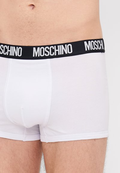 Biele bavlnené boxerky s čiernym elastickým pásom, na ktorom je bielym písmom logo "Moschino". Dizajn je priliehavý a hladký.