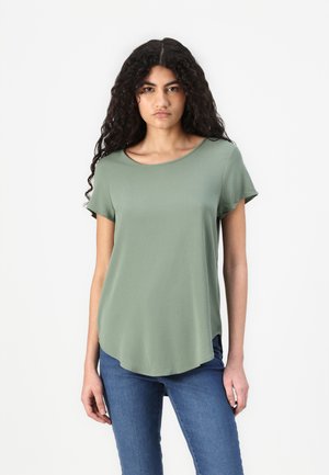 Korte mouwen t-shirt met een ronde hals in gedempt groen, met een gebogen zoom en een gladde textuur, gecombineerd met blauwe jeans.