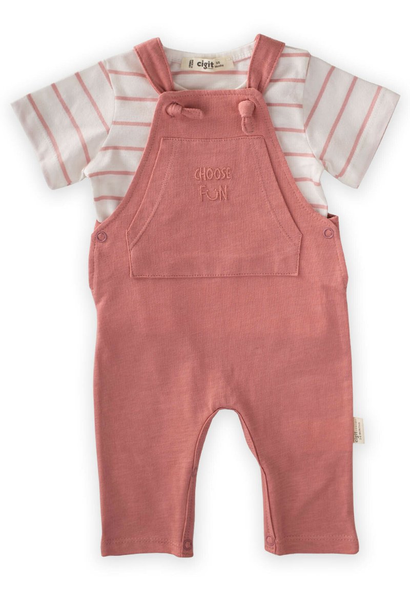 Peto rosa con una camiseta de rayas blanca y rosa debajo. El peto cuenta con un bolsillo con "ELIGE LA DIVERSIÓN" bordado y tirantes ajustables.
