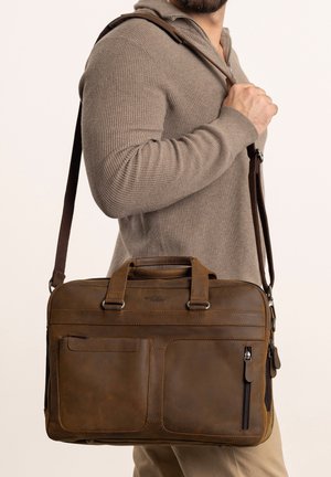 Brūns ādas portfelis ar divām augšējām rokturiem un noņemamu plecu siksnu, kas piedāvā vairākus rāvējslēdzēju un kabatu bez aizdari organizācijai.