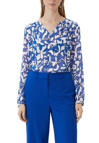 Blau-weiße gemusterte Bluse mit langen Ärmeln, V-Ausschnitt und Raffungen. Kombiniert mit einfarbigen blauen Hosen. Glatte Textur.