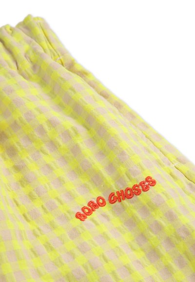 Yellow and beige checked fabric with an embroidered red text "Bobo Choses." Soft texture, relaxed shape with gathered waistband detail.